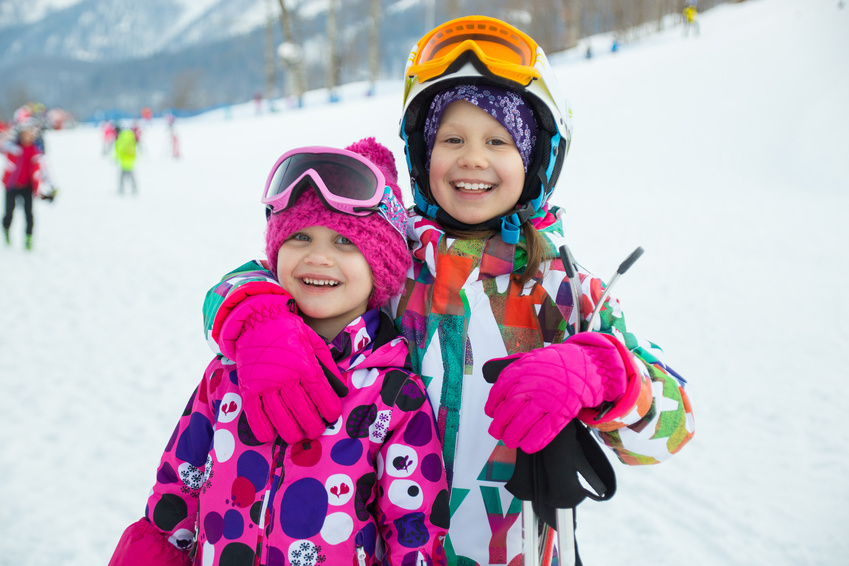 Portrait of two little girl in  ski helmet and mask in winter resort