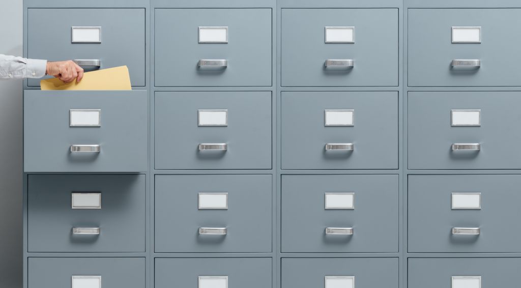 stokkete – stock.adobe.com Office worker taking a file from a filing cabinet drawer, business and administration concept