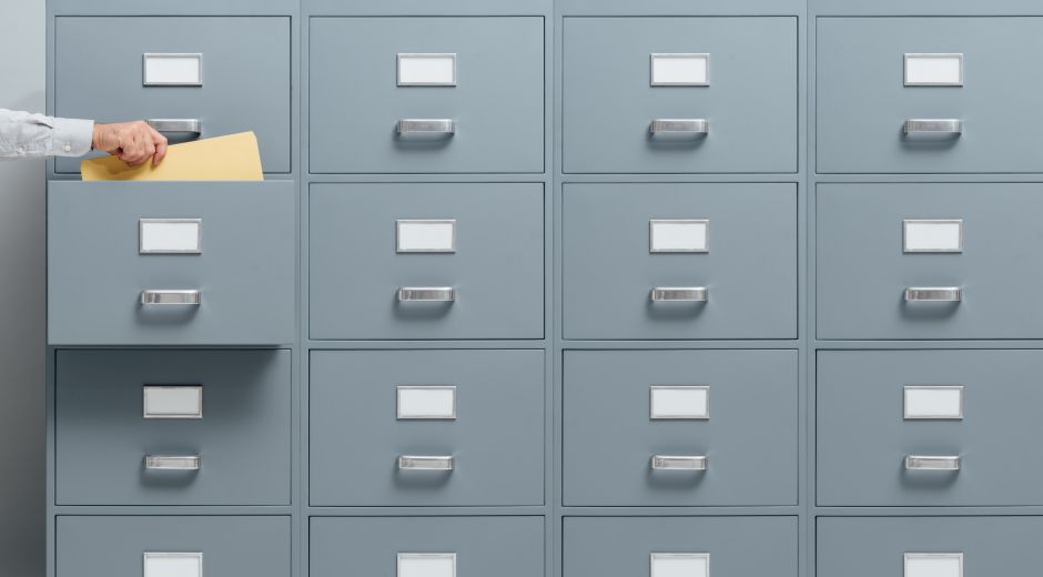 stokkete – stock.adobe.com Office worker taking a file from a filing cabinet drawer, business and administration concept